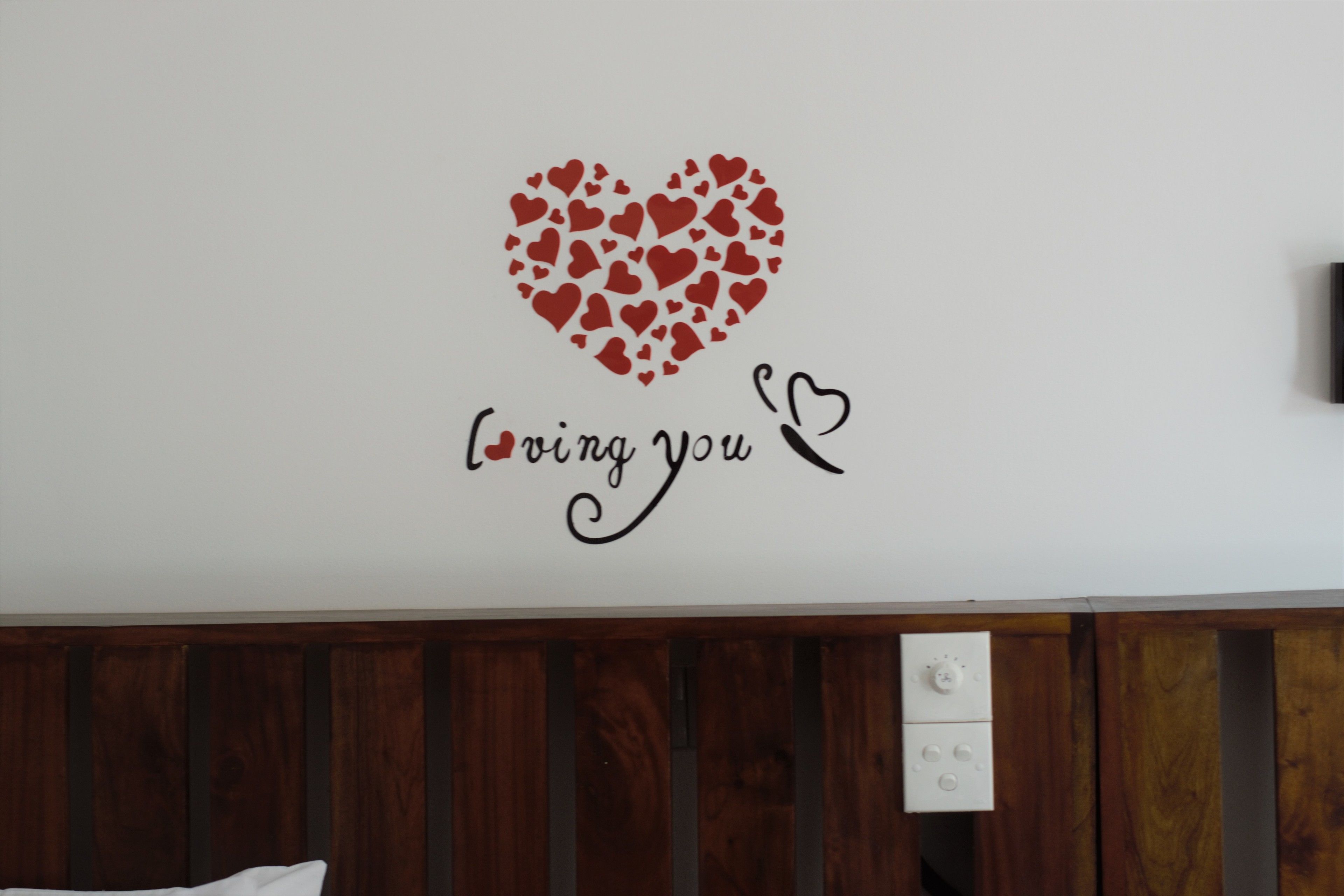 Una pared con un diseño en forma de corazón hecho con corazones más pequeños y el texto 'loving you' debajo.