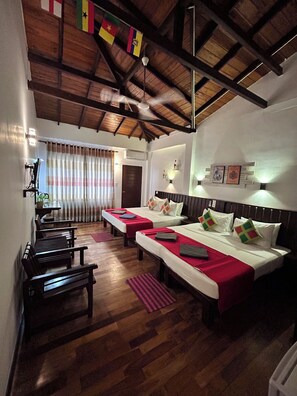 A hotel room with two beds, wooden flooring, a ceiling fan, and a view of the outdoors. - Cozy Sea View Inn (Hikkaduwa)