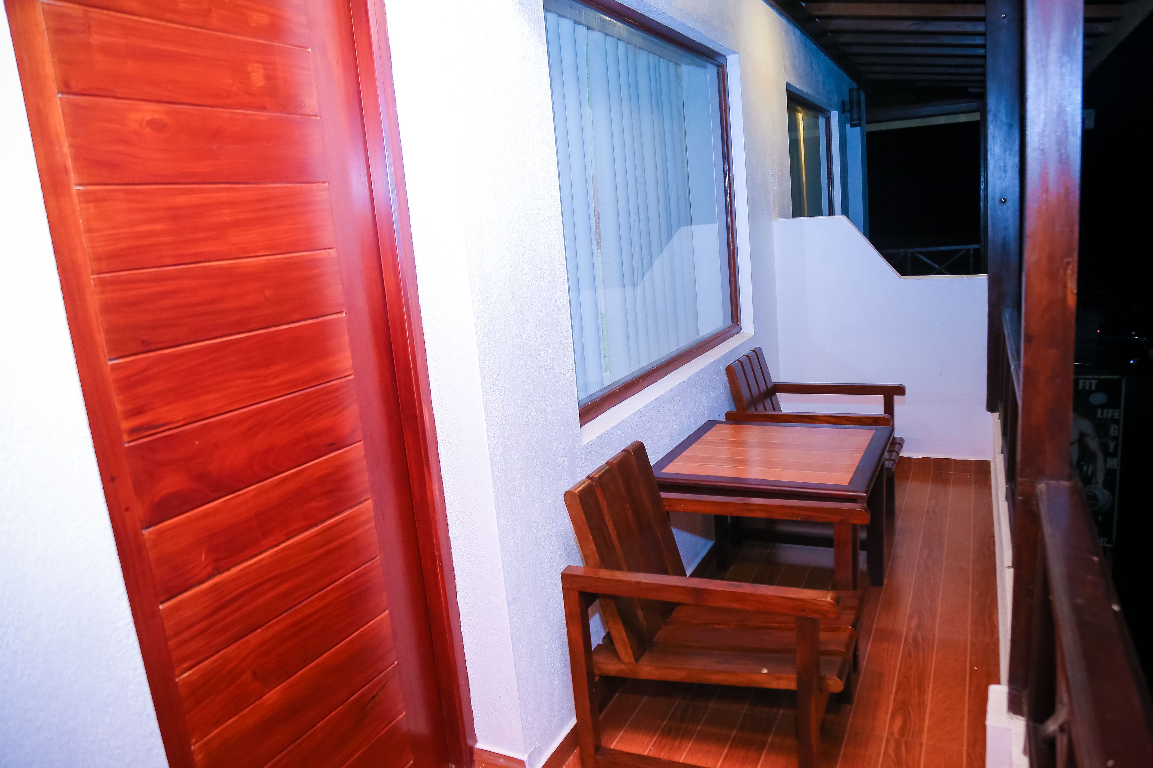 A wooden dining area with a table and chairs, a window with blinds, and a staircase leading to an upper level.