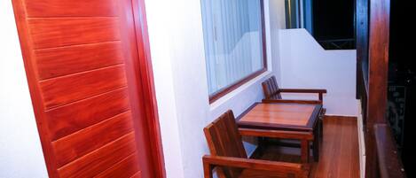Uma sala de jantar de madeira com mesa e cadeiras, uma janela com persianas, e uma escada que leva a um andar superior.