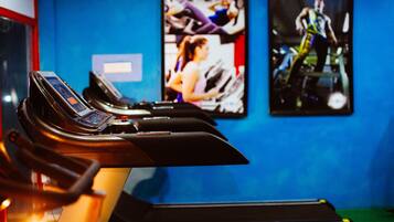 A treadmill in a gym with a blue wall and a poster of a person running.