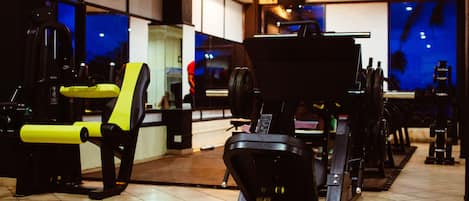 Un gimnasio con equipo de ejercicio, una cinta de correr y un espejo.