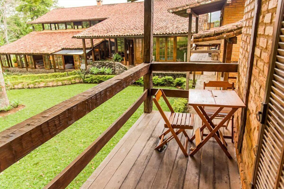 Una terraza de madera con una mesa y sillas, rodeada por un muro de ladrillo y un jardín.