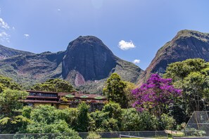 A mountain landscape with a traditional building featuring a tiled roof and multiple windows. - Pousada das Araras (Petrópolis)