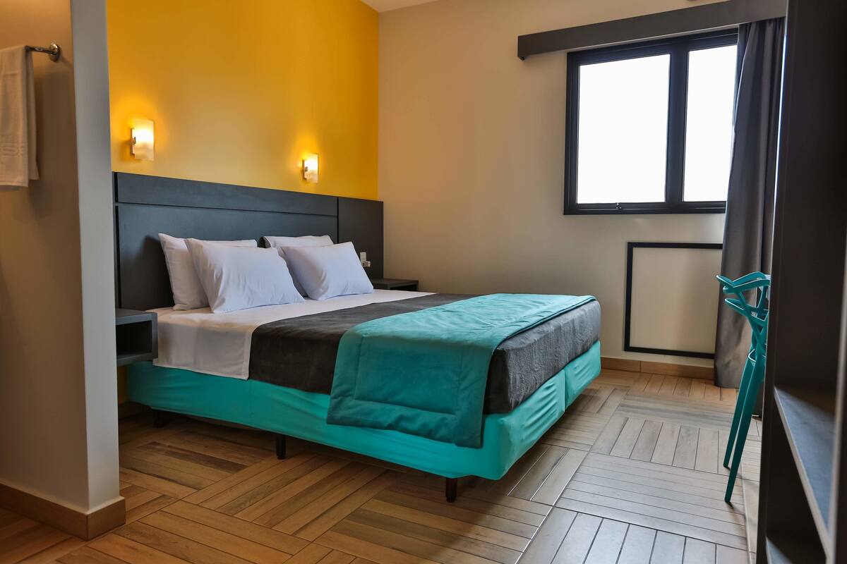 Une chambre d’hôtel avec un lit, une fenêtre et une chaise.