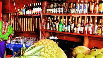 A bar with a television screen displaying 'Tanzania Safari' and shelves stocked with various liquor bottles.