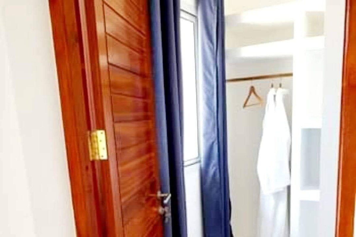 Une porte en bois avec une poignée en laiton, un rideau bleu et une armoire blanche dotée d’une tringle à vêtements.