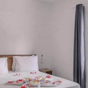 A hotel room with a neatly made bed, a wooden headboard, and a small bedside table. - Sipano Beach Lodge Kiwengwa (Kiwengwa)