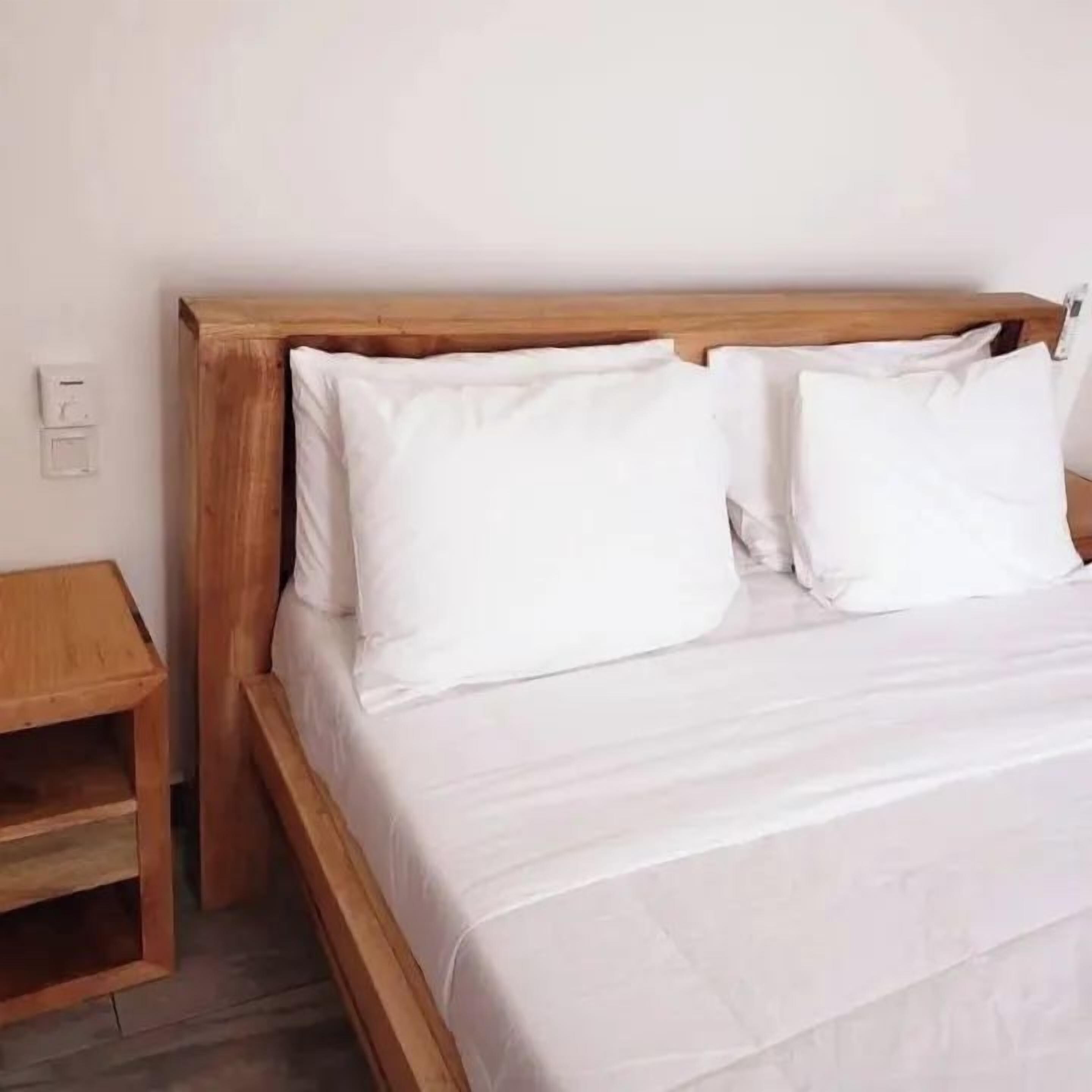 Een bed met een houten hoofdeinde en witte beddengoed.