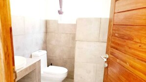 Ein Badezimmer mit Toilette, Waschbecken und Holztür.