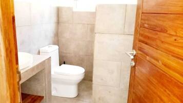 Ein Badezimmer mit Toilette, Waschbecken und Holztür.