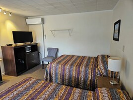 Una habitación de hotel con una cama, una silla, un escritorio con televisor y una lámpara.