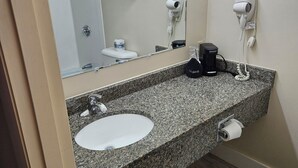 A bathroom with a granite countertop, a sink, a mirror, a towel rack, a hairdryer, and a toilet. - Brookside Inn (Smyrna Mills)