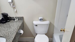 A bathroom with a toilet, a towel rack, a hairdryer, and a coffee maker on the counter. - Brookside Inn (Smyrna Mills)