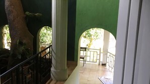 A corridor with a tiled floor, a stone sculpture, and a green wall. - Ka Mario Guesthouse (Kandy)