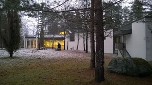 Een gebouw met een glazen gevel, omgeven door bomen en een met sneeuw bedekte grond.