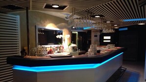 Een bar met een blauw verlichte toonbank, glazen en flessen.