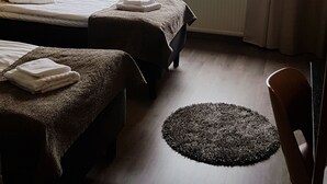 Een hotelkamer met twee bedden, uitzicht op een meer, een rond vloerkleed en een stoel.