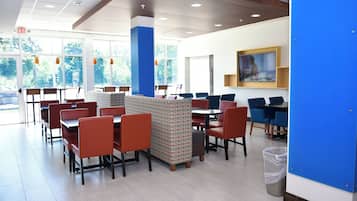 Un comedor moderno con mesas y cabinas, ventanas amplias y una pared de acento azul.