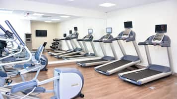 A gym with multiple treadmills, stationary bikes, and elliptical machines.
