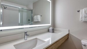 Un baño moderno con un espejo grande, un lavabo, un inodoro y una cabina de ducha de vidrio.