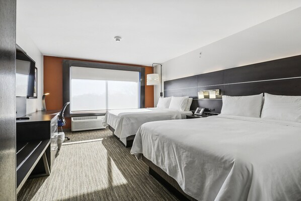 Hotelkamer met twee bedden, een bureau, een stoel, een televisie en een groot raam.