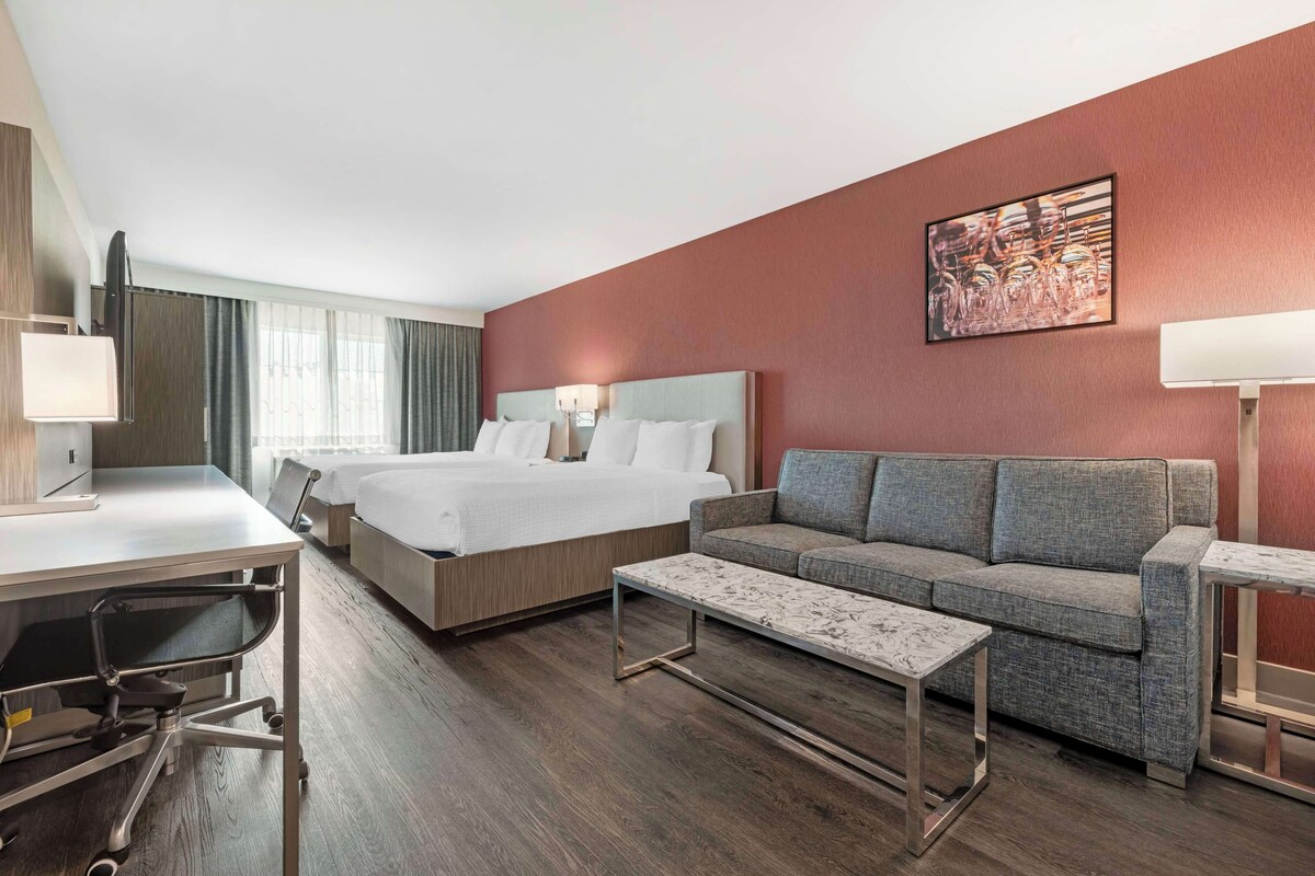 Una habitación de hotel con una cama grande, un sofá, un escritorio y una mesa de centro.
