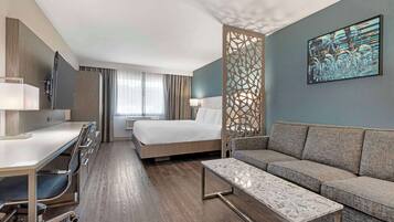 Une chambre d’hôtel comprenant un lit, un canapé, un bureau avec une chaise, une télévision et un paravent décoratif.