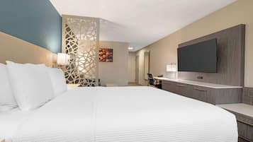 Quarto de hotel moderno com uma cama grande, televisão de tela plana na parede, escrivaninha com cadeira e um painel decorativo.