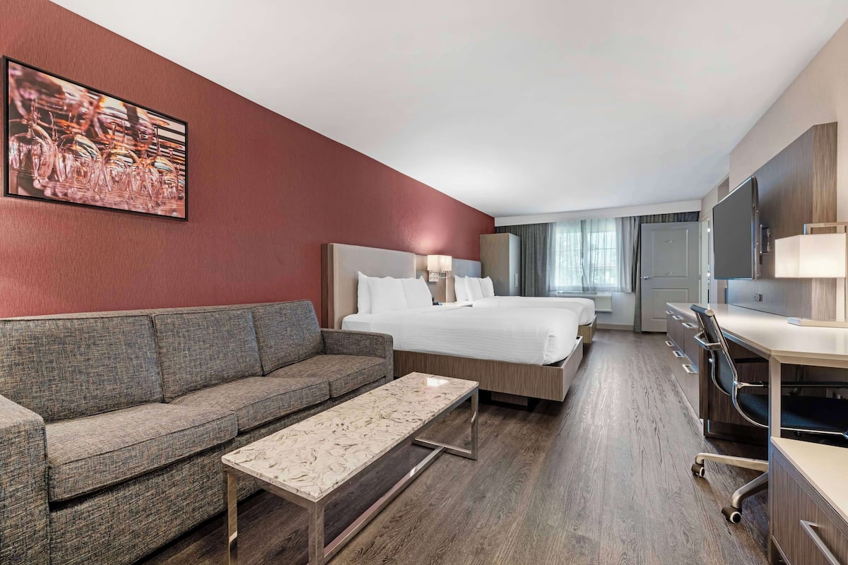 Una habitación de hotel con cama, sofá, escritorio y televisión.