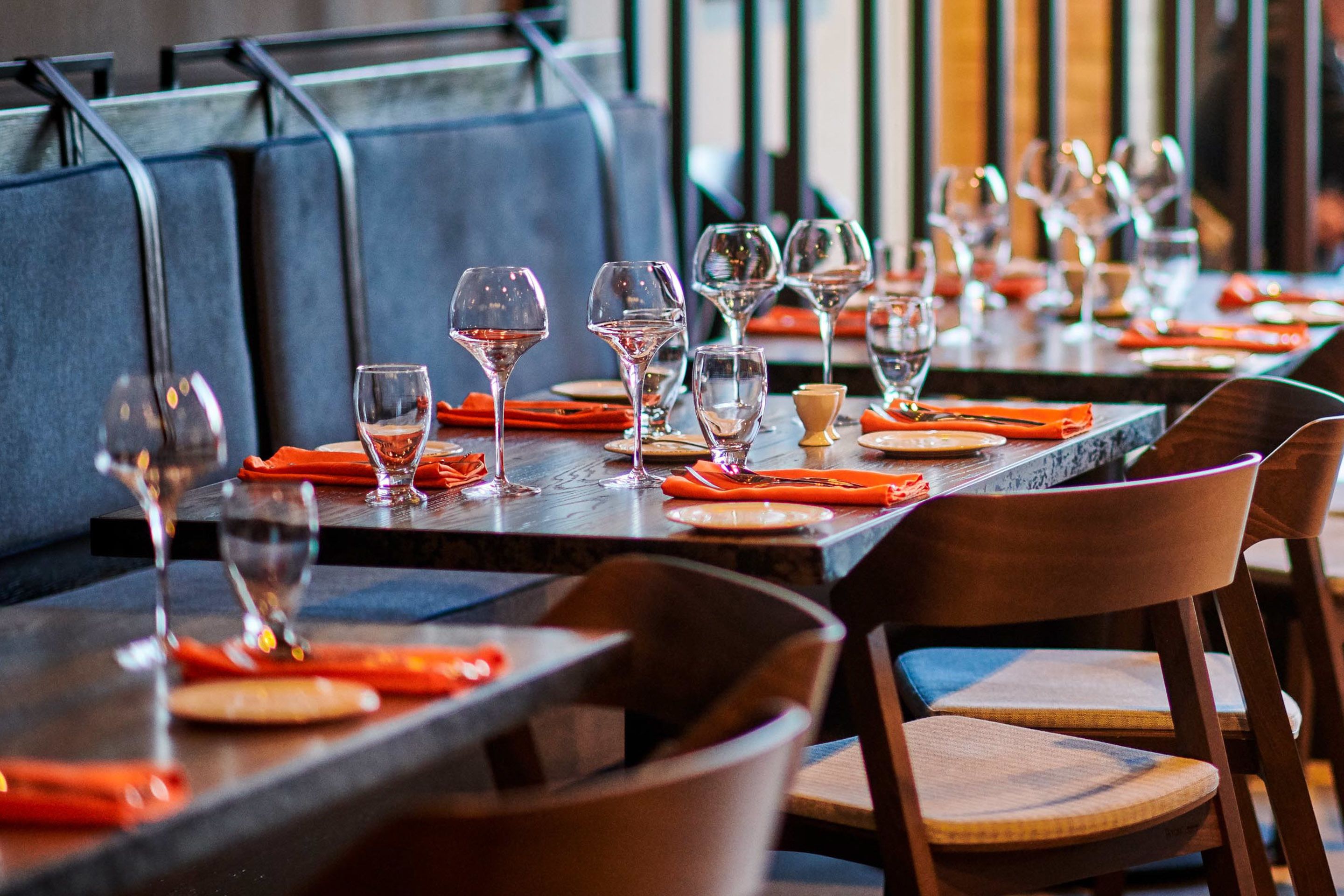 Interior de restaurante con mesas dispuestas para comer, con sillas de madera y un diseño moderno.