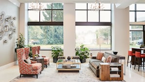 Un salón amplio con ventanas grandes, muebles modernos y una araña.