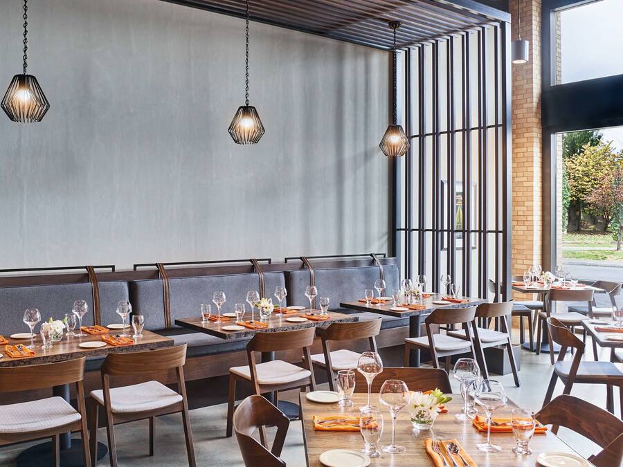 A restaurant with a modern interior, featuring wooden tables and chairs, and hanging pendant lights.