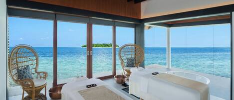 A room with two beds, a large window, and a view of the ocean.