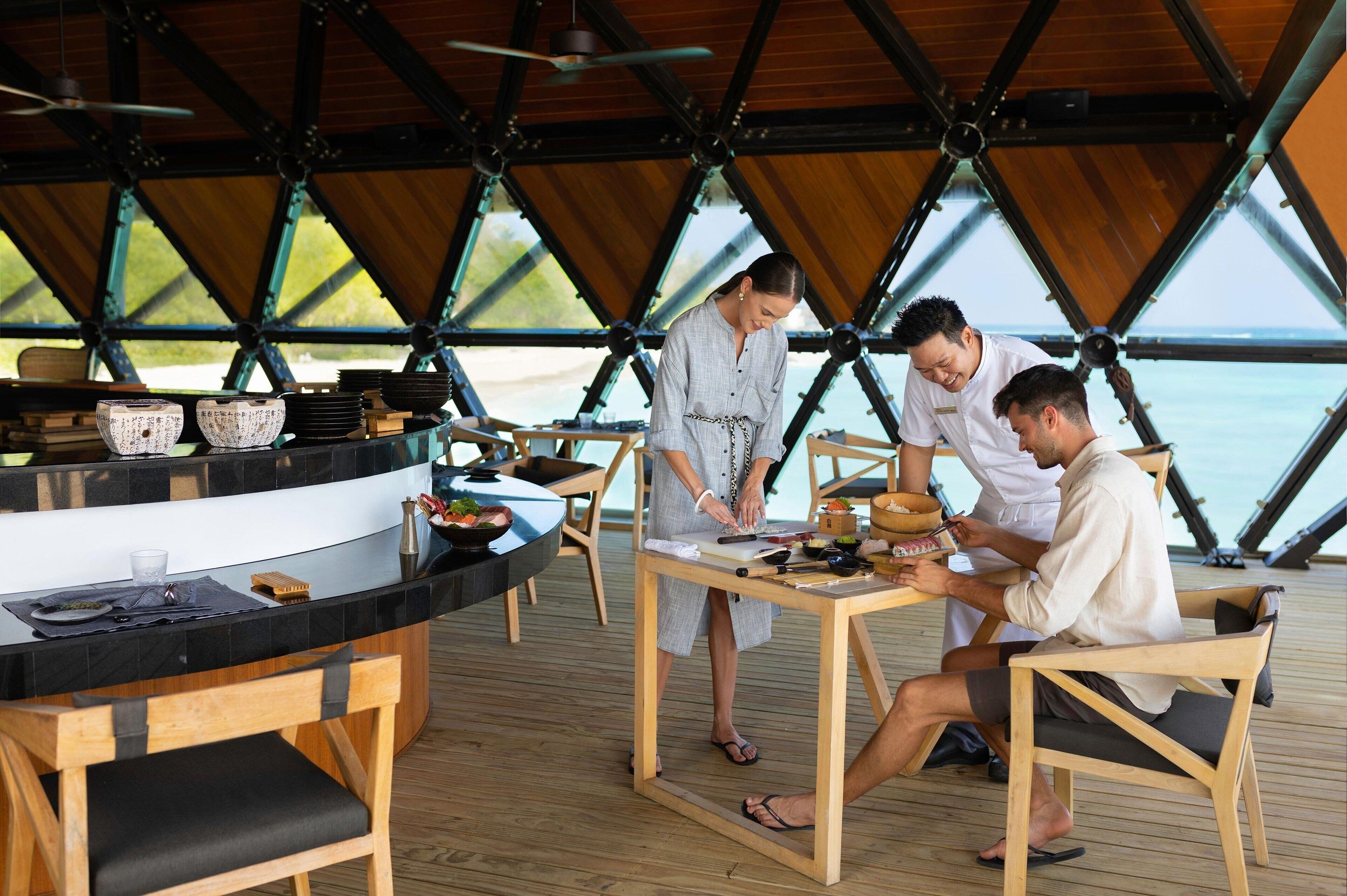 Un espace repas comprenant une table en bois, des chaises et un comptoir où sont disposés de la vaisselle.