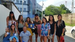 Un grupo de personas posando para una foto en un entorno exterior, con un edificio al fondo.