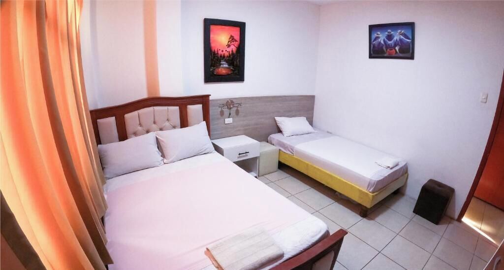 Un dormitorio con dos camas, una mesita de noche y una lámpara de pared.