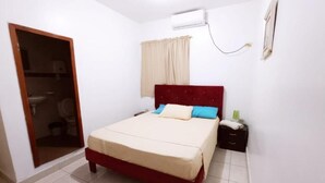 Un dormitorio con cama, armario, mesita de noche y ventana con cortinas.