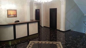 A reception area with a marble floor, a reception desk, and a framed picture on the wall. - Villa Le Grand (Boryspil)