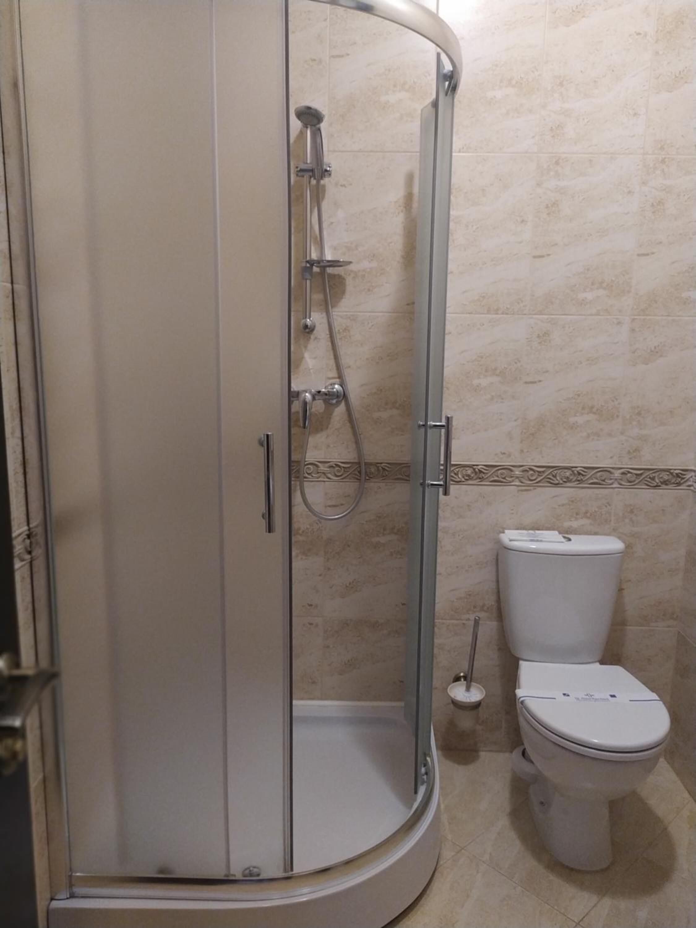 A bathroom with a glass-enclosed shower, a toilet, and a sink.