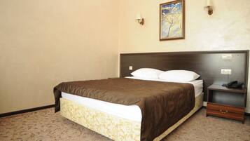 A hotel room with a large bed, a bedside table with a lamp, and a painting on the wall.