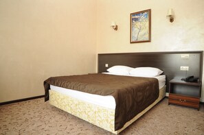 Un cuarto de hotel con una cama grande, una mesita de noche con lámpara y un cuadro en la pared.