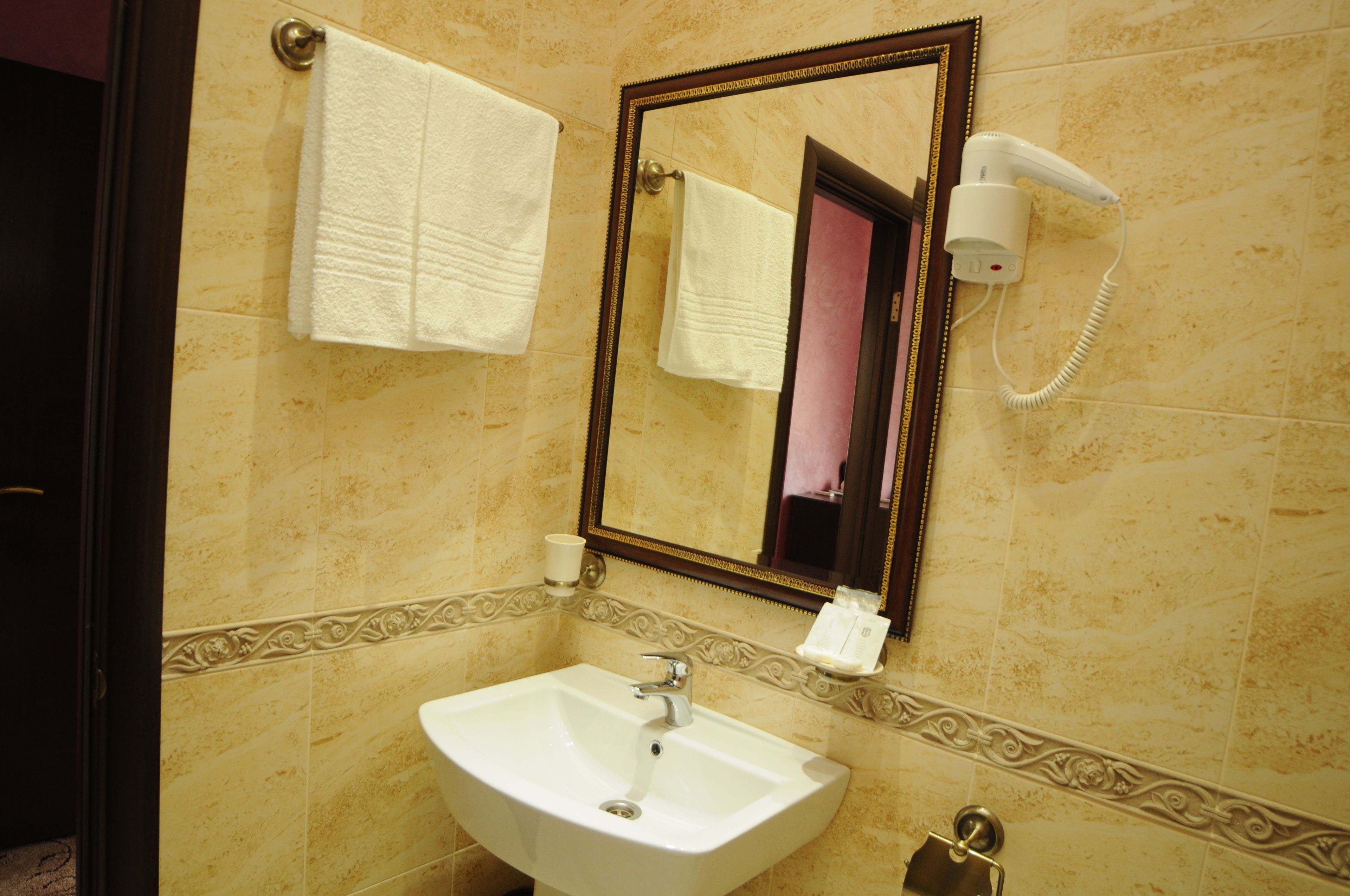 Un baño con lavamanos, espejo, toallero y secador de pelo.