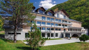 Un hôtel à plusieurs étages doté de balcons, d’une entrée couverte et surplombant un paysage montagneux.