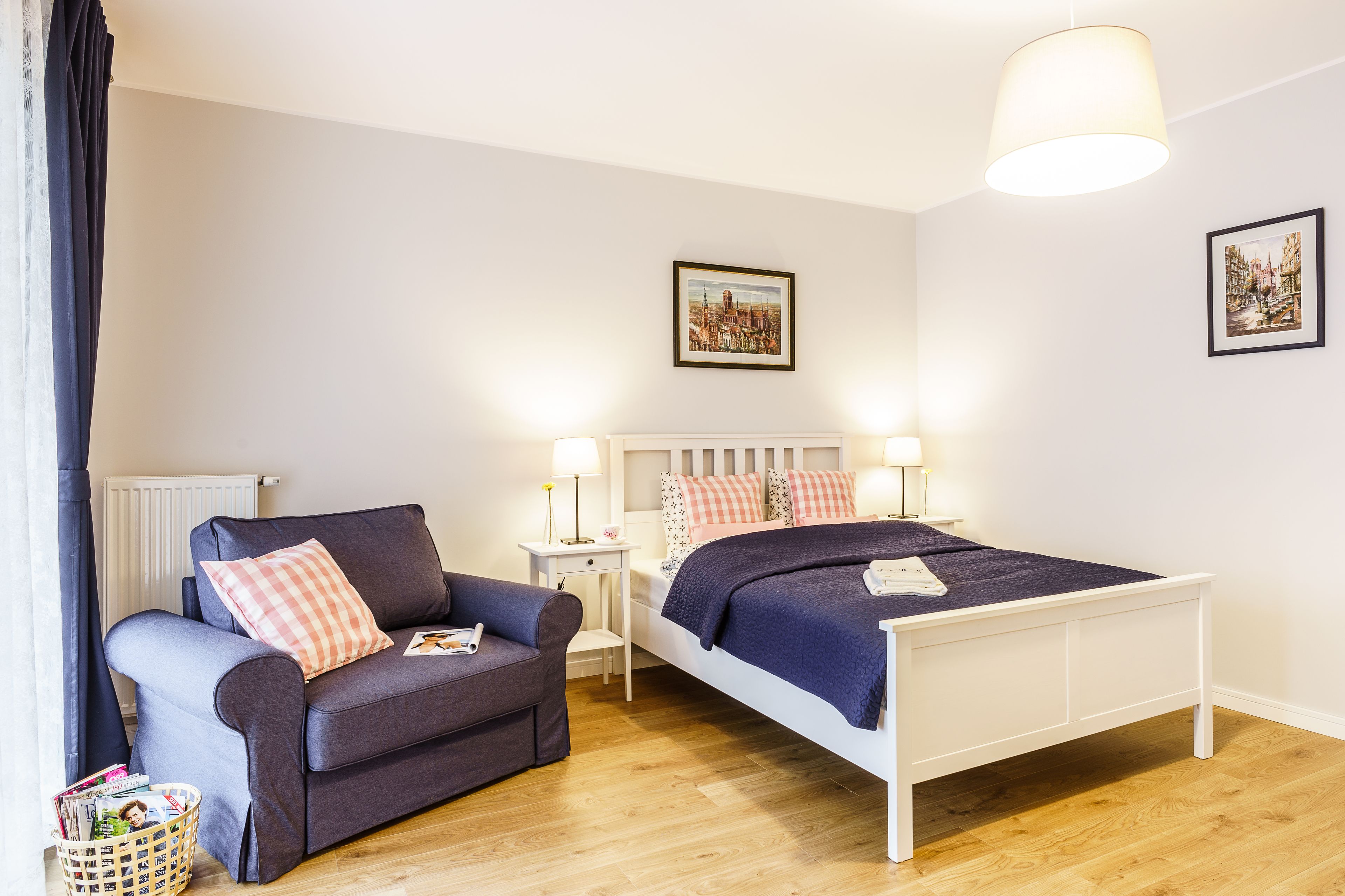 A bedroom with a bed, a chair, a nightstand, and a lamp.