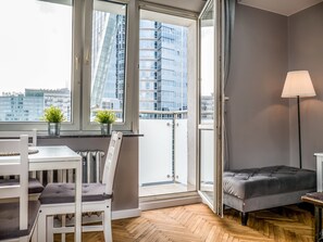 Una sala de estar moderna con balcón, comedor y sofá gris.
