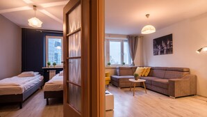 A modern apartment with a wooden floor, a sofa, a bed, and a small table. - 55 Plater Residence (Warsaw)