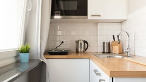 A modern kitchen with white cabinets, a stainless steel kettle, a toaster, and a sink. - 55 Plater Residence (Warsaw)