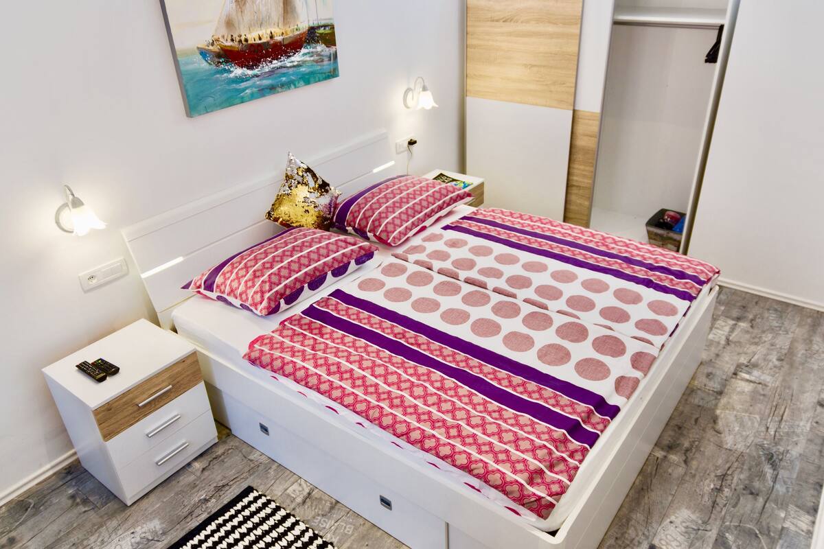 Un dormitorio moderno con cama, mesita de noche y un cuadro en la pared.