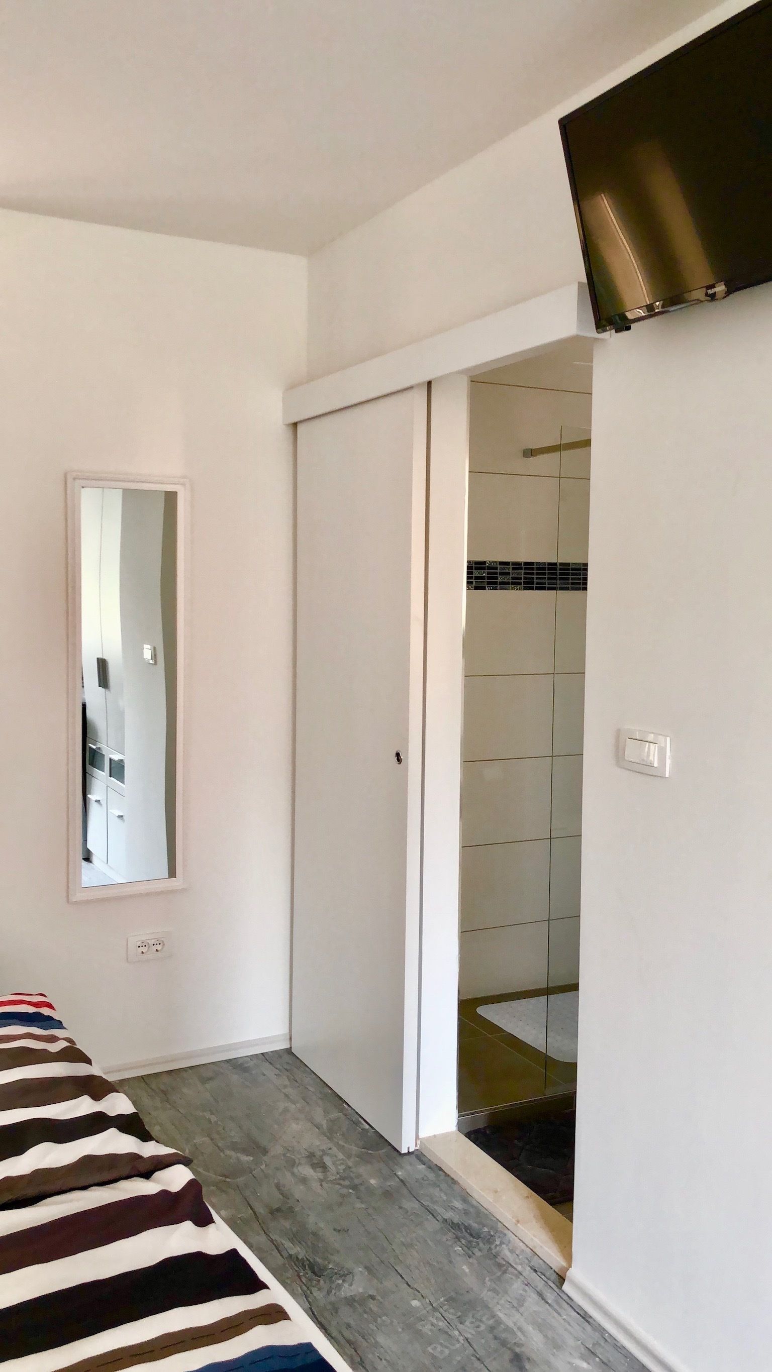 Une chambre à coucher comprenant un lit, un miroir, une armoire et une salle de bain avec douche.